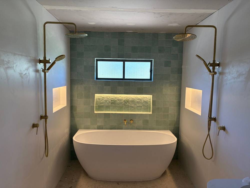 Bathroom renovation with lit wall niches and twin showers